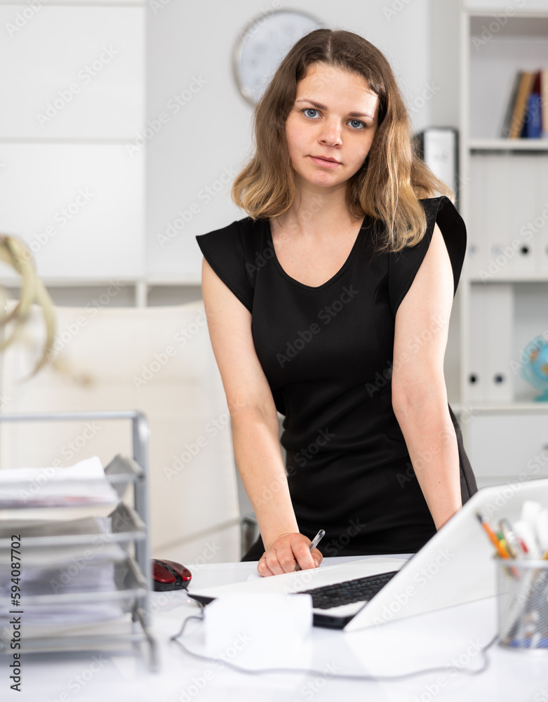 Woman accountant posing at her working table in office during workday.