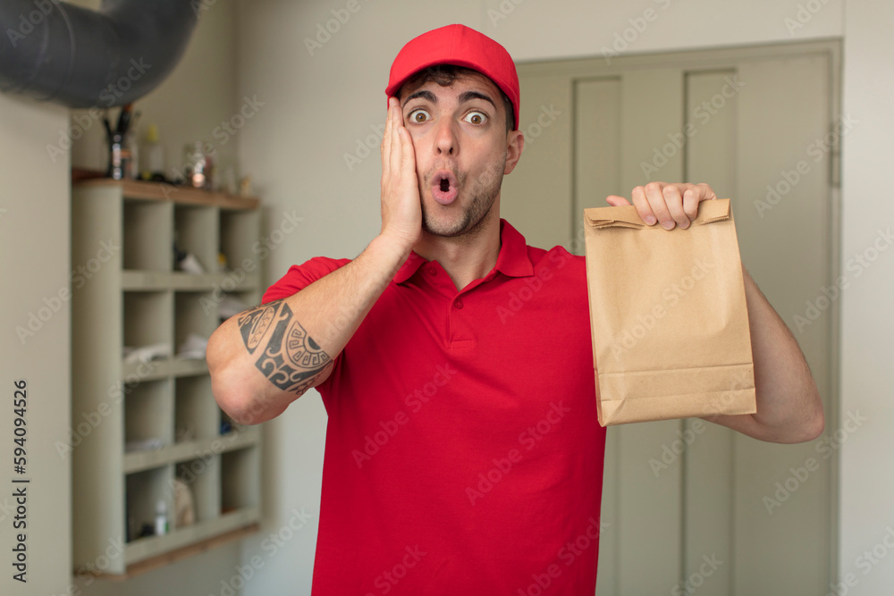 young handsome man feeling extremely shocked and surprised. delivery man concept young handsome man feeling extremely shocked and surprised. delivery man concept