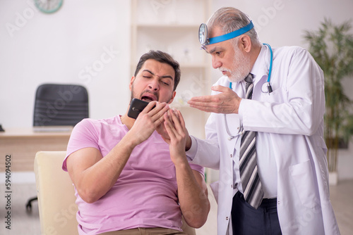 Young male patient visiting old male doctor otologist