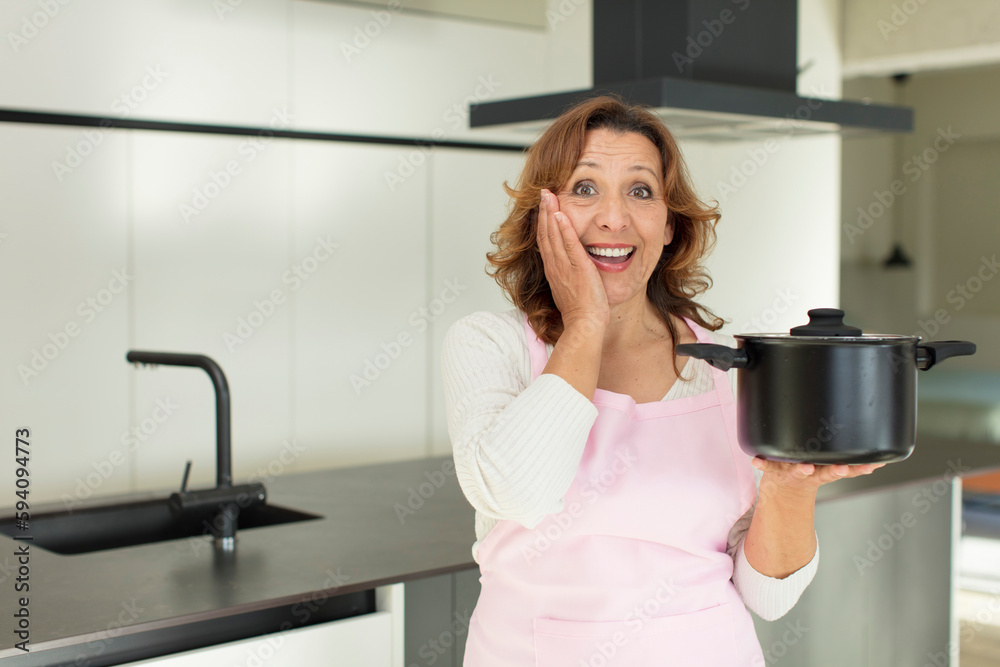 middle age pretty woman feeling happy and astonished at something unbelievable. cooking at home concept