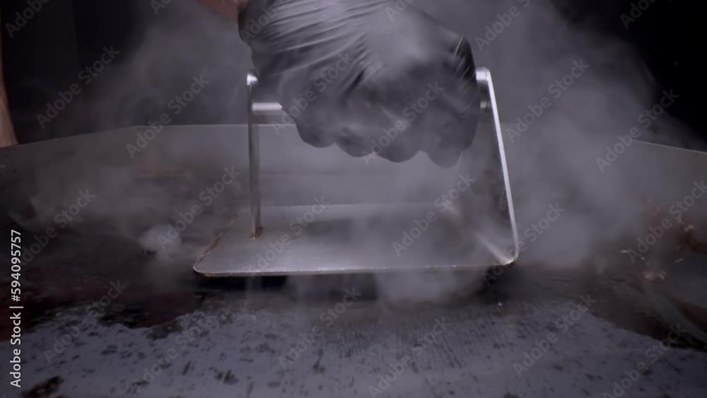 Closeup of person preparing smash burger on grill