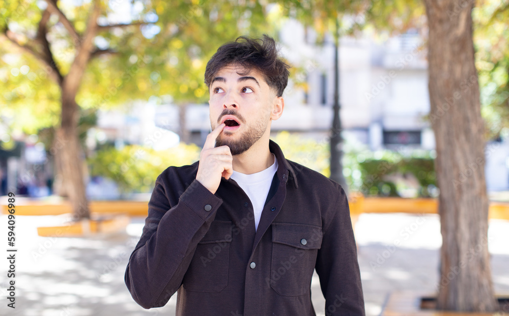 young handsome man with surprised, nervous, worried or frightened look, looking to the side towards copy space young handsome man with surprised, nervous, worried or frightened look, looking to the side towards copy space