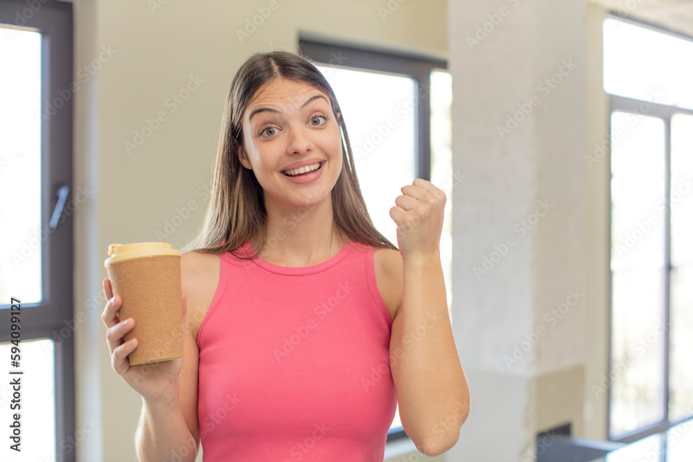 young pretty woman feeling shocked,laughing and celebrating success. take away coffee concept
