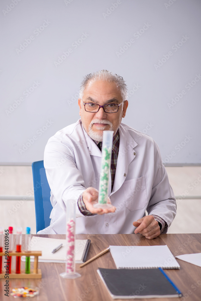 Old male teacher chemist sitting in the classroom Old male teacher chemist sitting in the classroom
