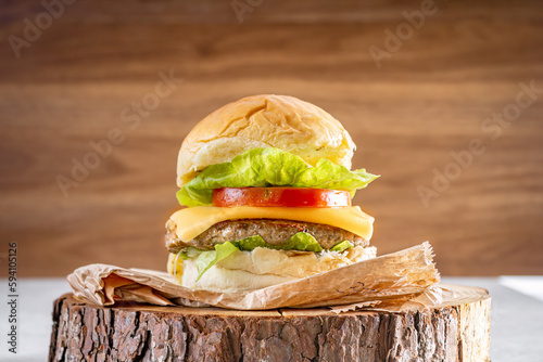 Delicious hamburger with cheddar cheese over wooden log and wooden background. photo