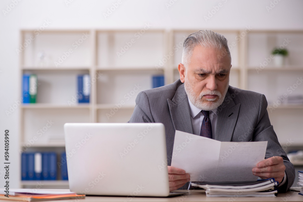 Old male employee working in the office Old male employee working in the office