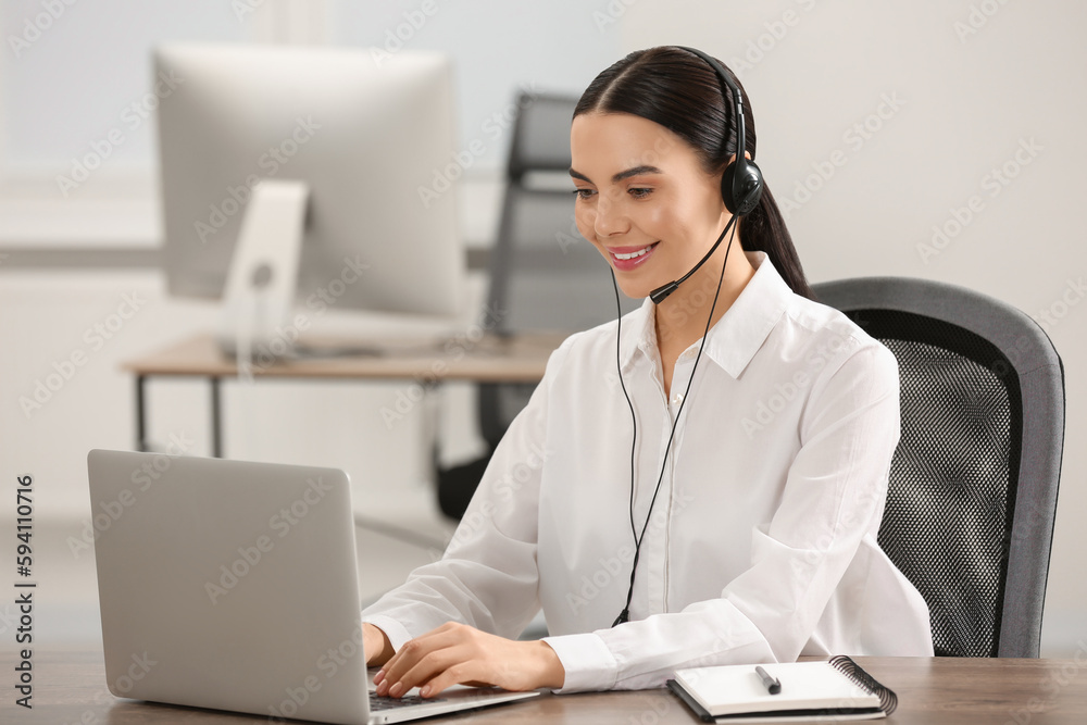 Hotline operator with headset working on laptop in office Hotline operator with headset working on laptop in office