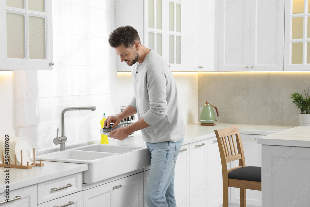 Man washing plate above sink in kitchen Man washing plate above sink in kitchen