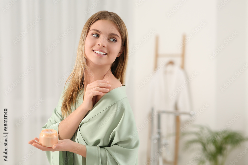 Beautiful happy woman in stylish robe applying cream in bathroom. Space for text Beautiful happy woman in stylish robe applying cream in bathroom. Space for text