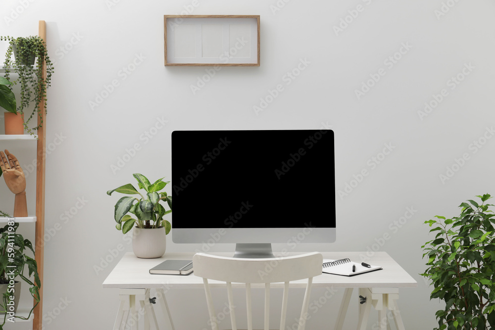Spacious workspace with desk, chair, computer and potted plants at home Spacious workspace with desk, chair, computer and potted plants at home