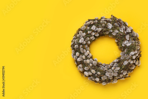 Wreath made of beautiful willow flowers on yellow background, top view. Space for text