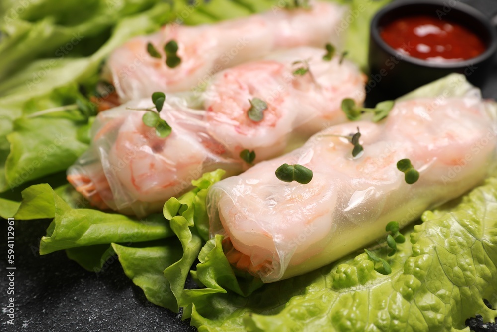 Tasty spring rolls served with lettuce and microgreens on grey textured table, closeup Tasty spring rolls served with lettuce and microgreens on grey textured table, closeup