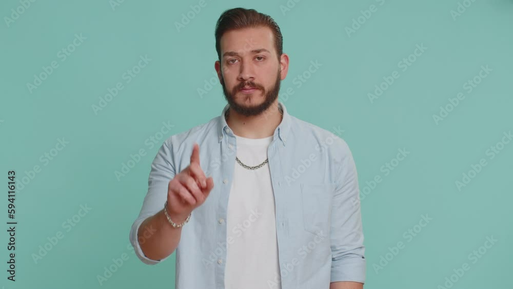 Lebanese handsome man shakes finger and saying No, be careful, scolding, giving advice to avoid danger mistake, disapproval sign. Young guy isolated alone on blue studio background. People lifestyle Lebanese handsome man shakes finger and saying No, be careful, scolding, giving advice to avoid danger mistake, disapproval sign. Young guy isolated alone on blue studio background. People lifestyle