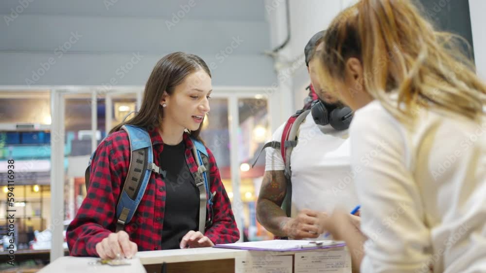 4K Asian woman hostel receptionist giving information and check in shared bedroom to guest. Lower-priced inn service with shared accommodations and bunk beds for backpacker tourist on travel trip.