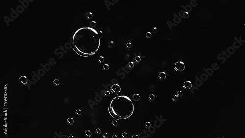Top view closeup scene on small bright white bubble fuse together to be a bigger and break isolated on black background, fizz texture of soda water when gas release photo