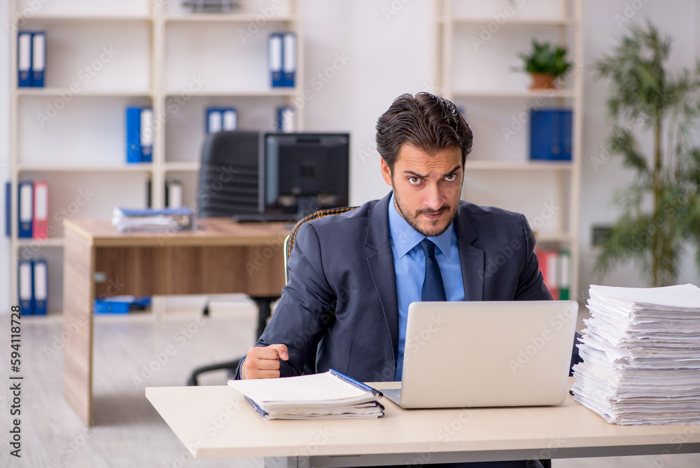 Young male employee and too much work in the office Young male employee and too much work in the office