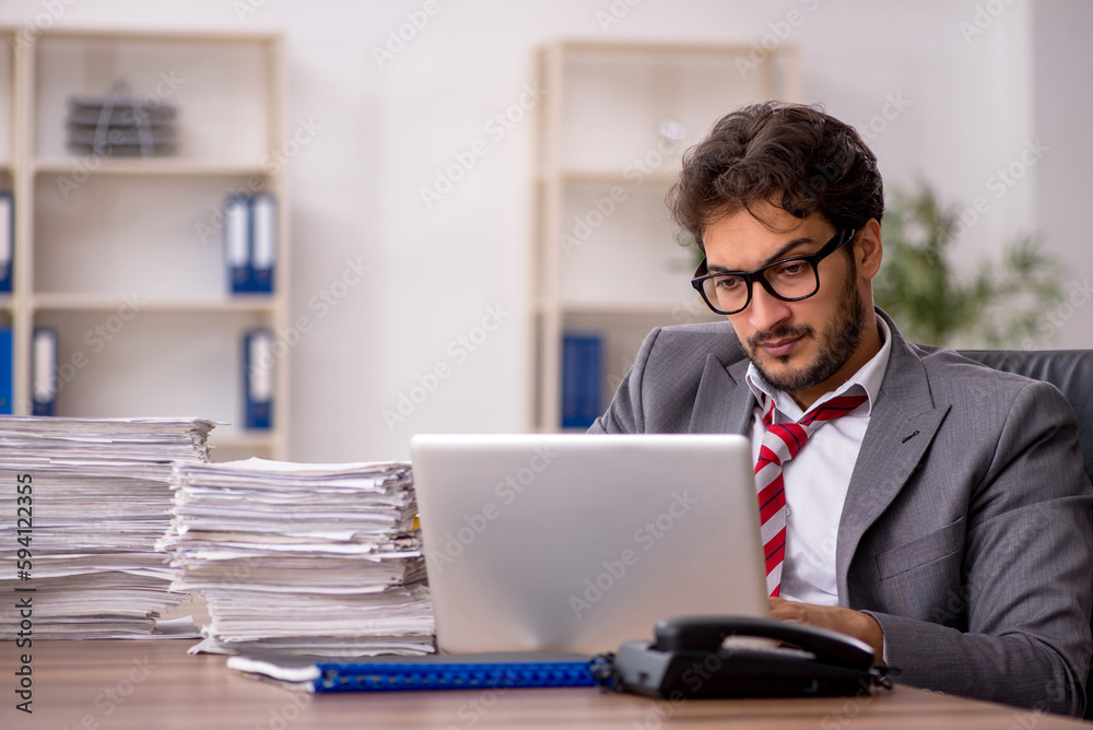 Young male employee unhappy with excessive work in the office Young male employee unhappy with excessive work in the office