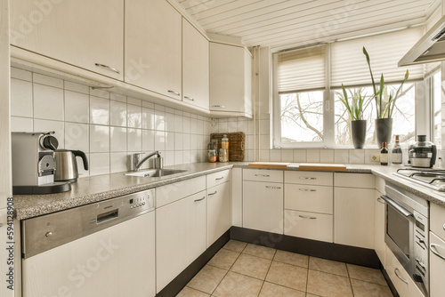 a small kitchen with white cabinets and appliances on the counter top, in front of a window that looks out onto the street