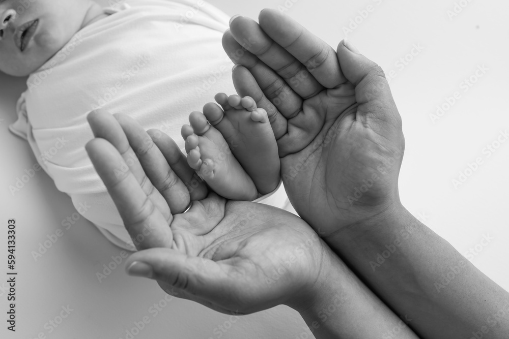 Black and white shade beautiful shape hands of mother, hold tiny newborn baby feet on black background with love, care, family safety and protection, child with premature birth concept or NICU care Black and white shade beautiful shape hands of mother, hold tiny newborn baby feet on black background with love, care, family safety and protection, child with premature birth concept or NICU care