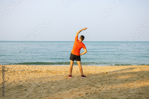 man doing stretching exercises on beach summer outdoors.  healthy active lifestyle.