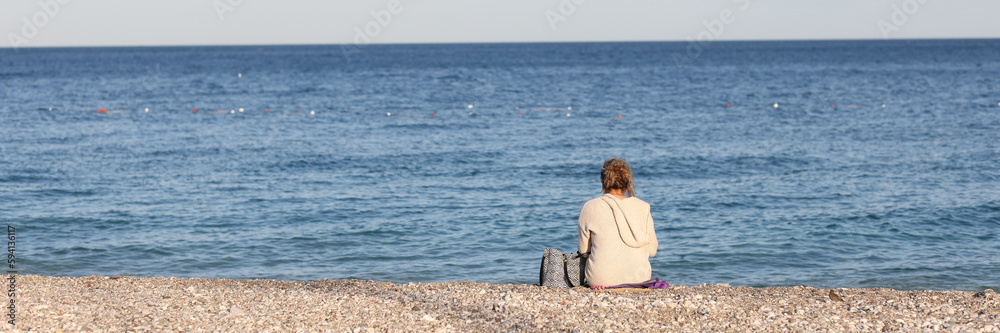 Woman sitting on pebbles beach near sea