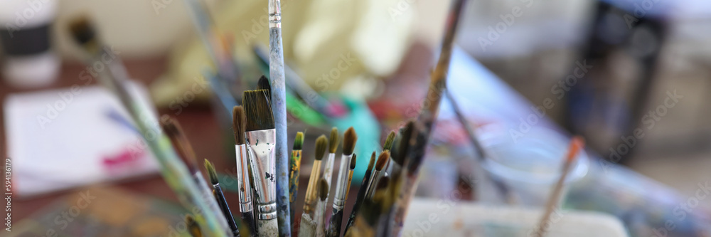Obraz premium Glasses with paint brushes at artist workplace