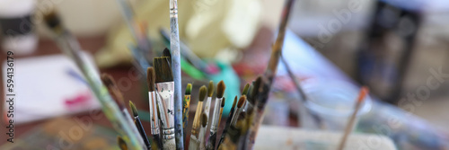 Glasses with paint brushes at artist workplace