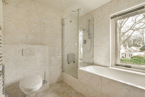 a bathroom with a toilet  shower and bathtub in front of a window looking out to the garden outside