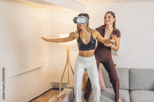 Women having fun using virtual reality goggles at home