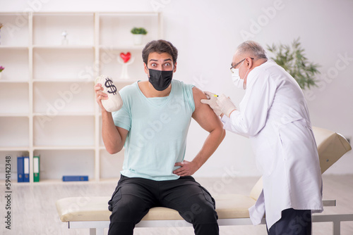 Male patient giving moneybag to doctor