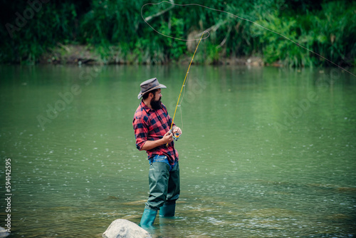 Fisherman using rod flyfishing in mountain river. A fly fisherman fishing for wild trout on the river in the forest.
