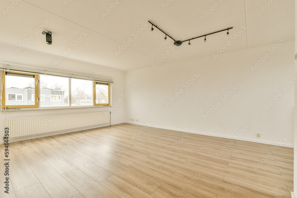 an empty room with wood flooring and large windows in the corner is very clean, but it's hard to see how an empty room with wood flooring and large windows in the corner is very clean, but it's hard to see how