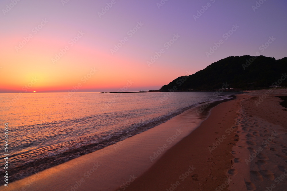 美しい海岸の夕陽が水平線に沈む風景です。