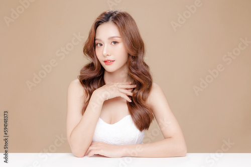 Young Asian beauty woman curly long hair with korean makeup style on face and perfect skin on isolated beige background. Facial treatment, Cosmetology, plastic surgery. photo