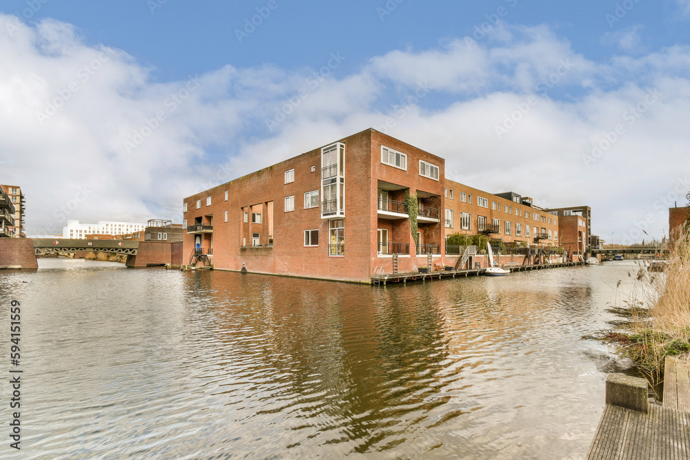some buildings on the side of a body of water with clouds in the sky above it and an overcast blue sky