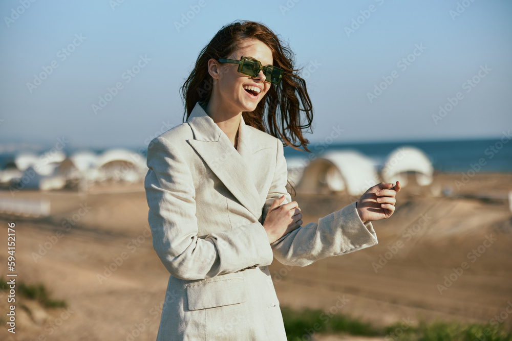 stylish woman with red hair standing on the coast in sunglasses laughing stylish woman with red hair standing on the coast in sunglasses laughing
