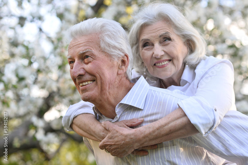 elderly man holding an old woman on his back in summer