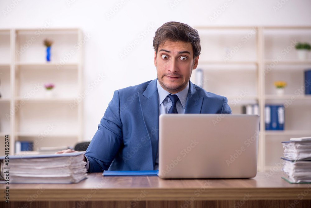 Young male employee and too much work in the office Young male employee and too much work in the office
