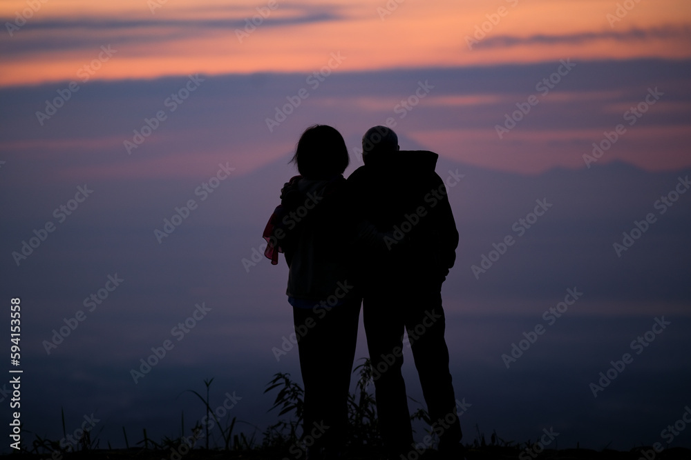 Silhouette of man and woman standing on a hilltop to see the sunrise