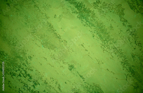 Green background from decorative plaster with abstract spots. Unusual green wall texture with beautiful patterns, creative surface background. Front covering for facing of buildings.