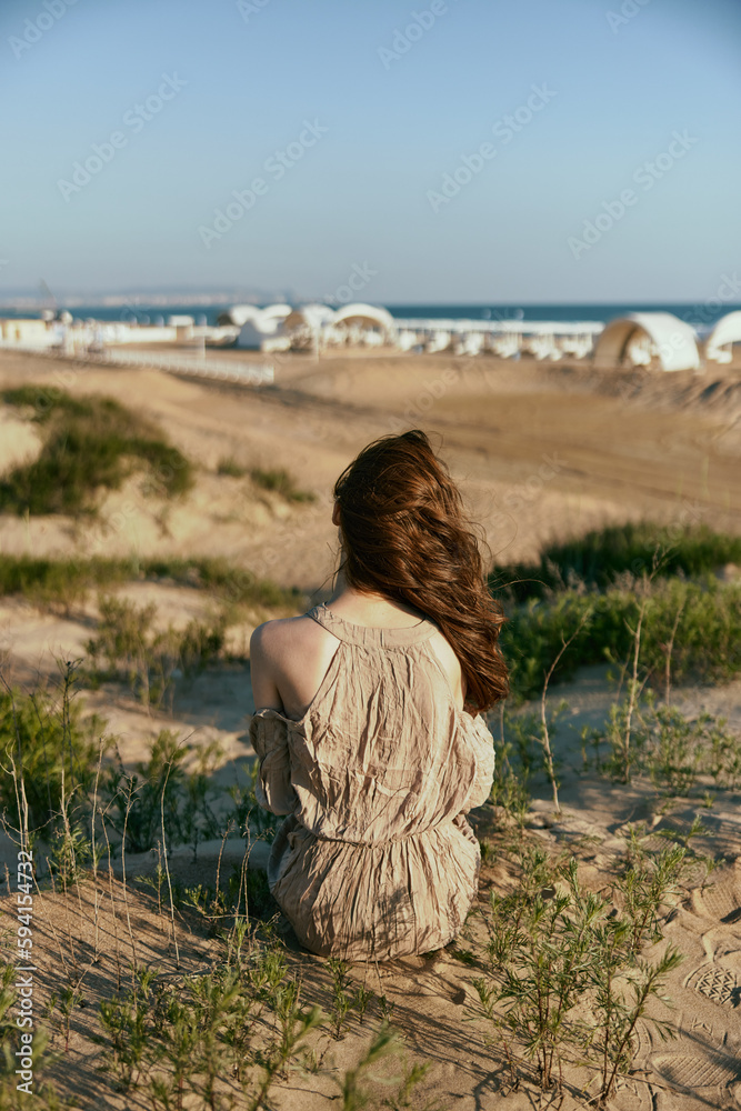 a woman sits with her back to the camera on the sea coast enjoying the sea view a woman sits with her back to the camera on the sea coast enjoying the sea view