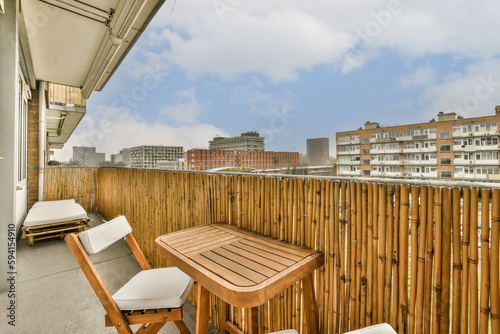 a balcony with chairs and a table on the outside deck looking out onto the cityscaped buildings in the background