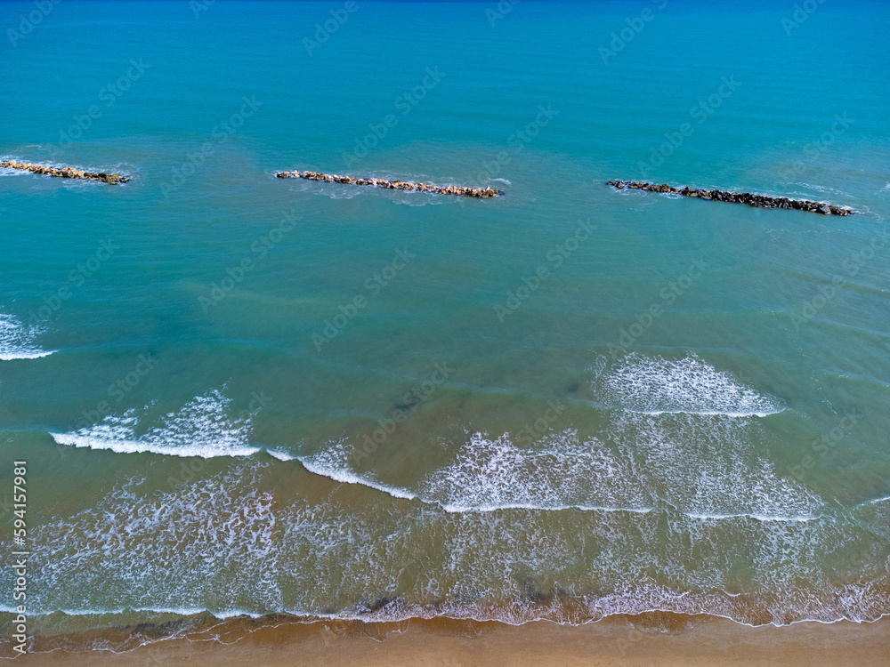 Aerial view landscape Italy Pescara. Empty beach and sea, waves, sand, rocks. Photo from a drone. Blue sky.