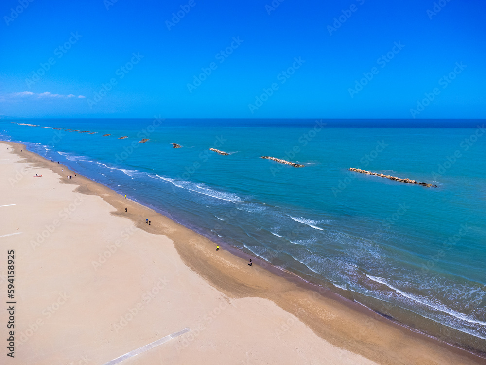 Aerial view landscape Italy Pescara. Empty beach and sea, waves, sand, rocks. Photo from a drone. Blue sky.