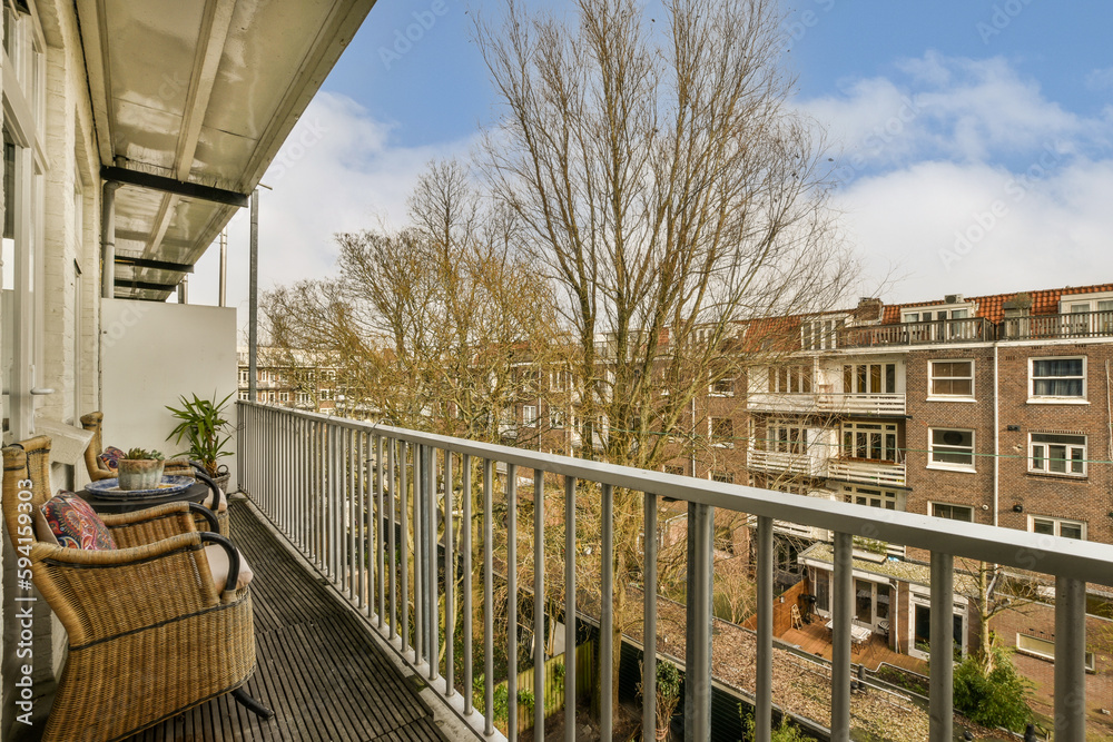 a balcony with a chair and tree in the foreground, taken from an apartment building's roof terrace