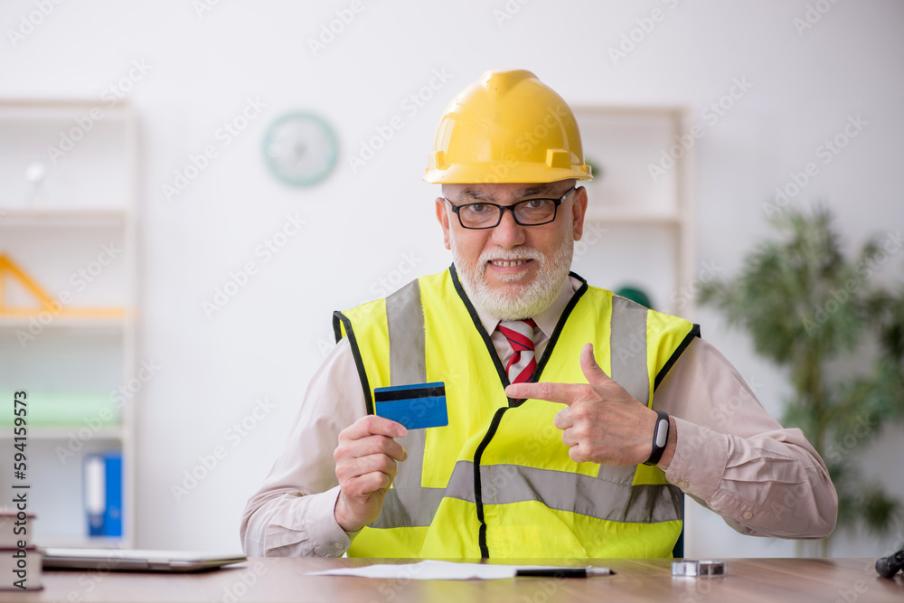 Old male architect holding credit card Old male architect holding credit card