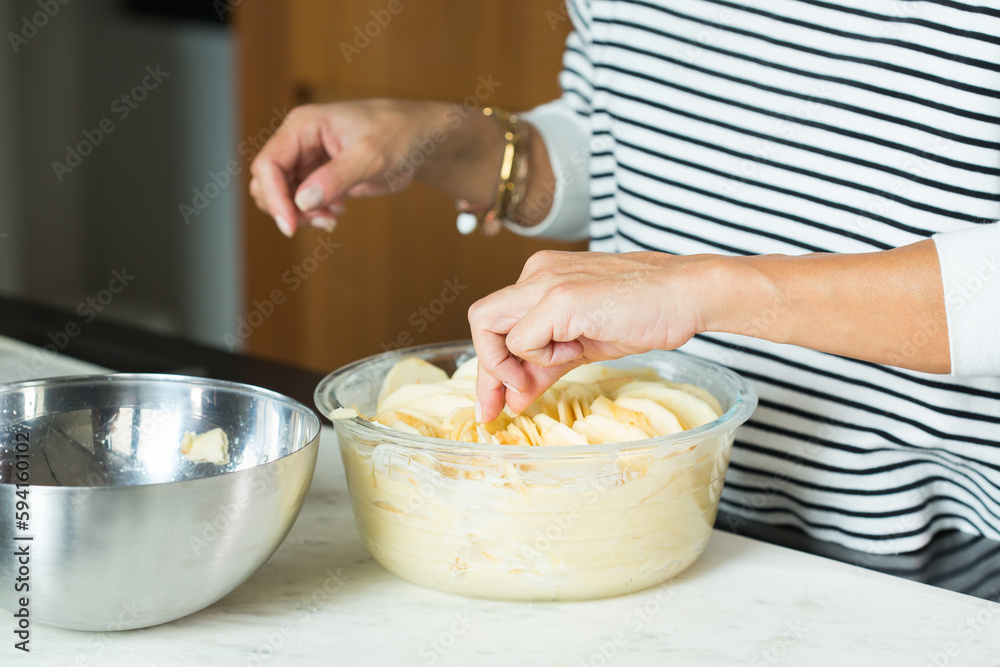 Woman hands putting apples while cooking apple pie Woman hands putting apples while cooking apple pie