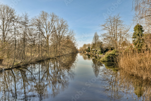 a river with trees and bushes in the fore, taken from a bridge over it's waterline on a sunny day