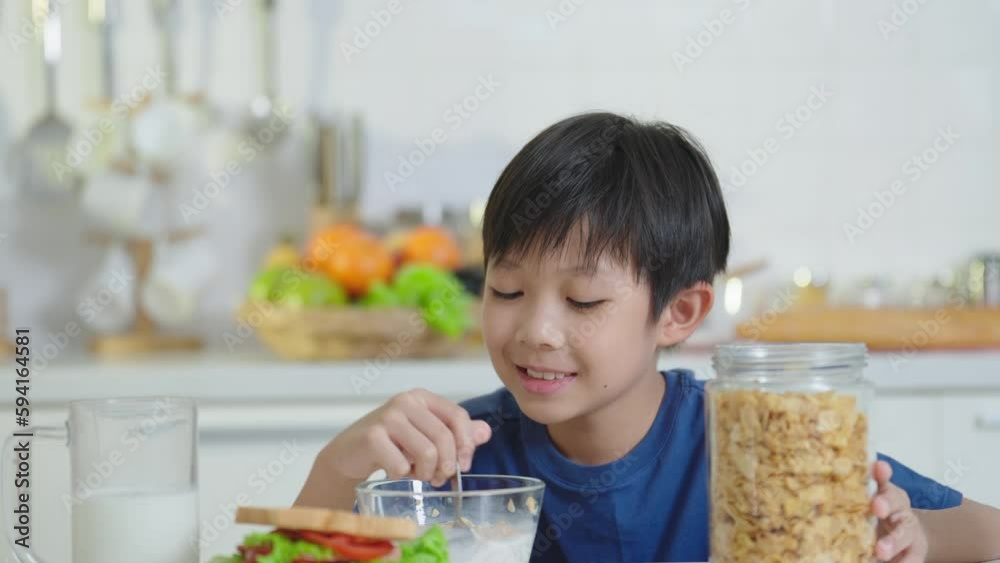 Asian little boy enjoy drinking milk from a glass with happiness sitting and holding glass of milk at breakfast time in the morning at home