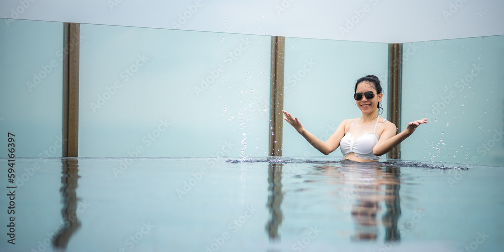 Portrait of a young smiling beautiful woman wearing white swimsuit and goggles while enjoying and relaxing in a swimming pool Portrait of a young smiling beautiful woman wearing white swimsuit and goggles while enjoying and relaxing in a swimming pool